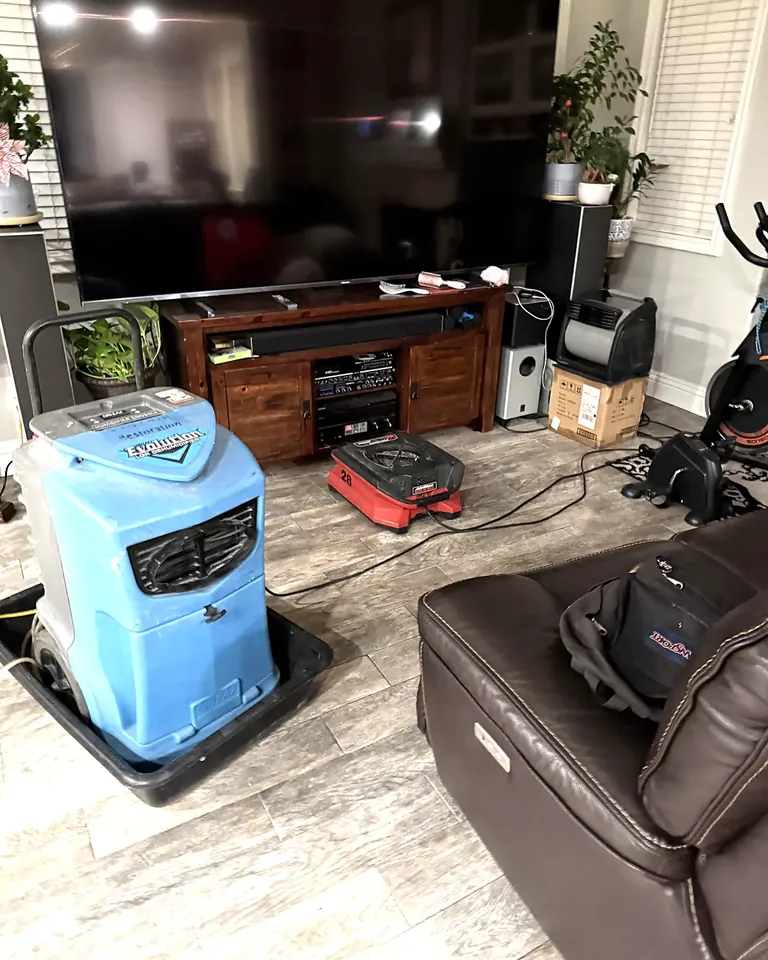 Commercial dehumidifier and air mover drying a living room floor