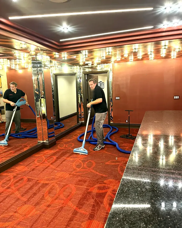 Two technicians running water extraction wands across a flooded carpet