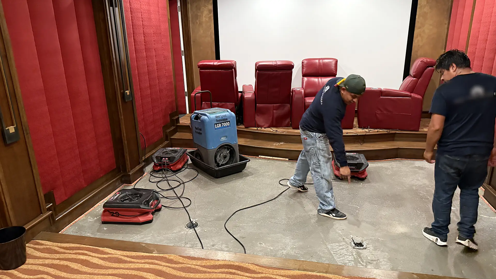 Flood Pro technicians drying a flooded home theater with a commercial dehumidifier and air movers